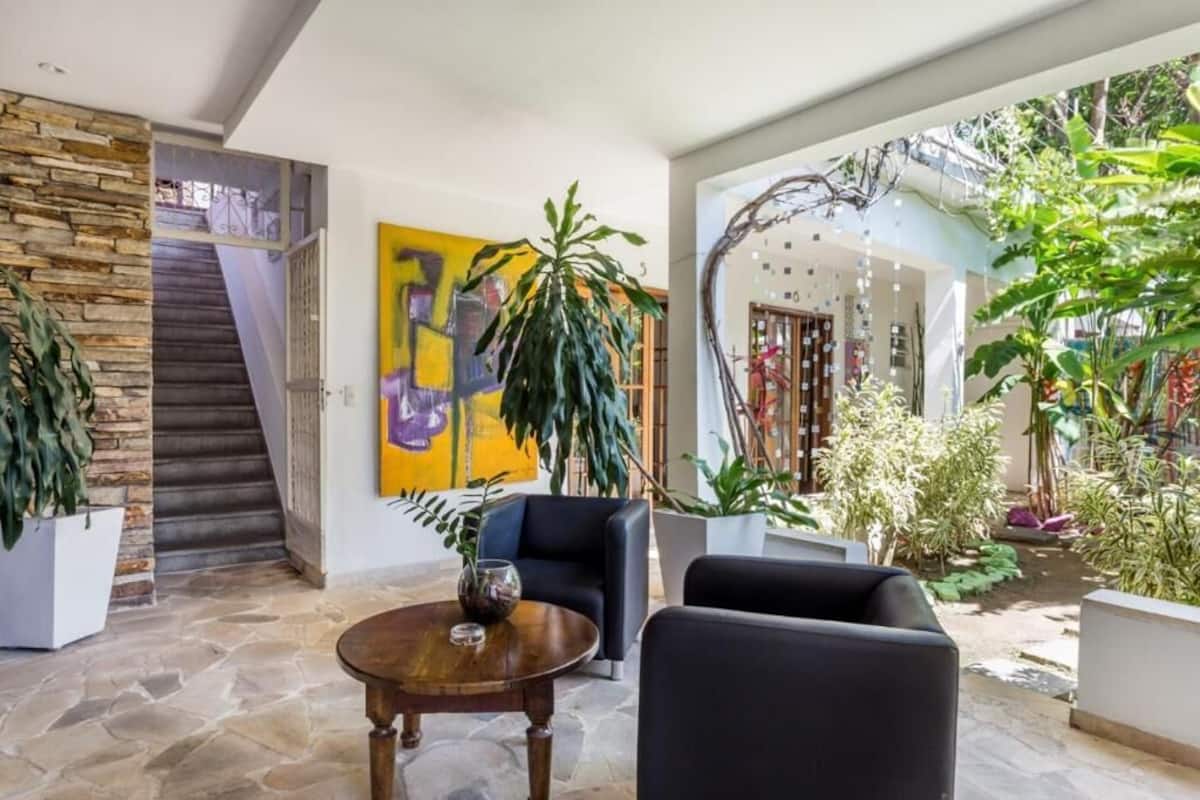 Ein modernes Interieur mit einer Steintreppe, einem großen abstrakten Gemälde und verschiedenen Pflanzen.