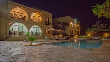 Um edifício amplo com várias varandas, piscina e área de estar externa.