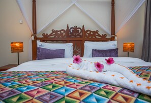 A bed with a geometric patterned bedspread, a wooden headboard, and two bedside lamps. - Mzima Beach Resort (Diani Beach)