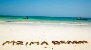 A beach with the words 'MARINA BAHAMAS' written in the sand, boats in the water, and a clear sky. - Mzima Beach Resort (Diani Beach)