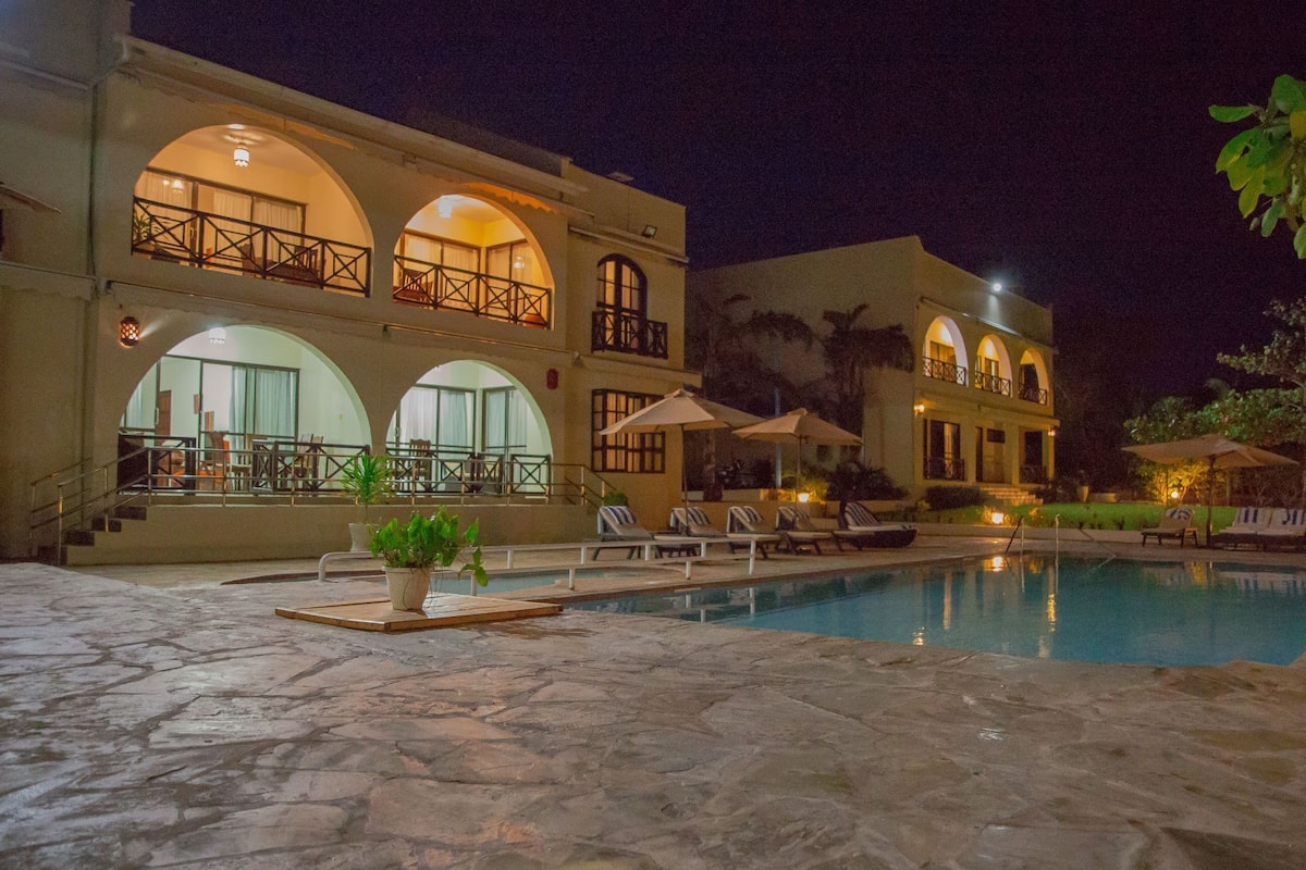 A large building with multiple balconies, a swimming pool, and outdoor seating.