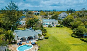 A large house with a swimming pool, multiple outdoor seating areas, and a well-maintained lawn. - Mzima Beach Resort (Diani Beach)