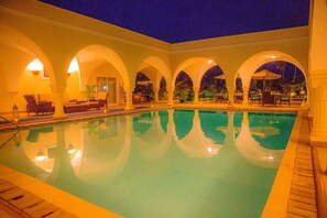 A swimming pool with arched ceilings and lounge chairs. - Mzima Beach Resort (Diani Beach)