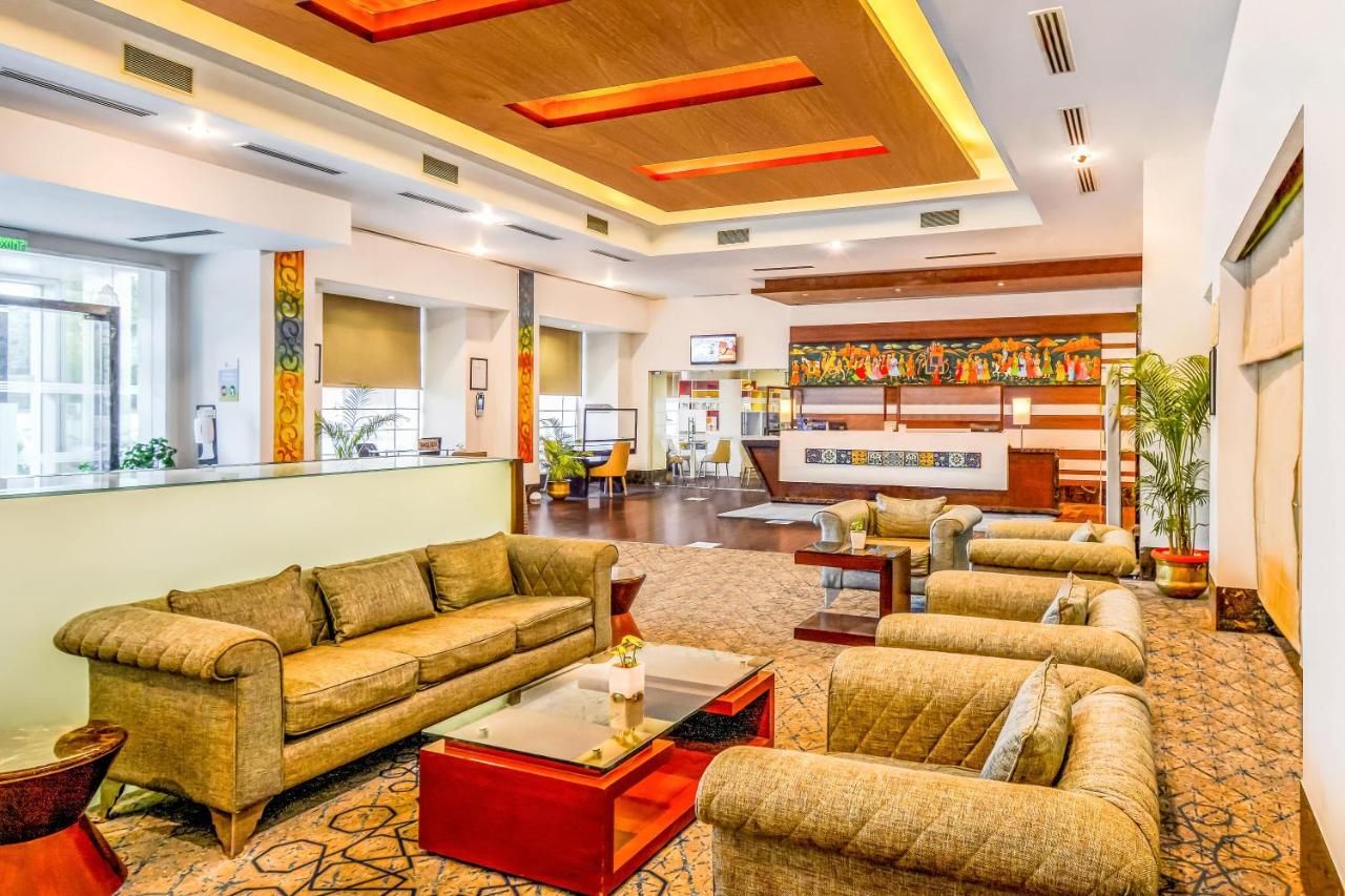 A hotel lobby with a reception desk, sofas, a coffee table, and a mural.