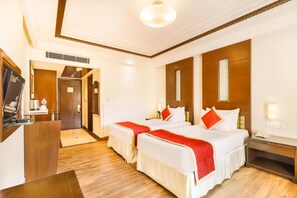 A hotel room with two beds, a desk, a TV, and a minibar. - Club Mahindra Jaipur (Jalsu)