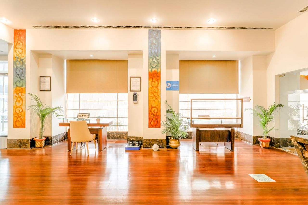 A spacious lobby with a reception desk, two potted plants, and a piano.