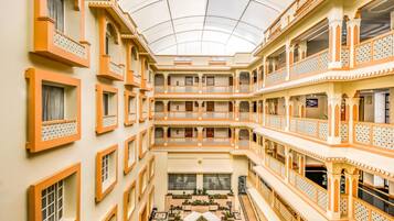 Un atrio de varios niveles con balcones, un patio central y un techo de cristal.