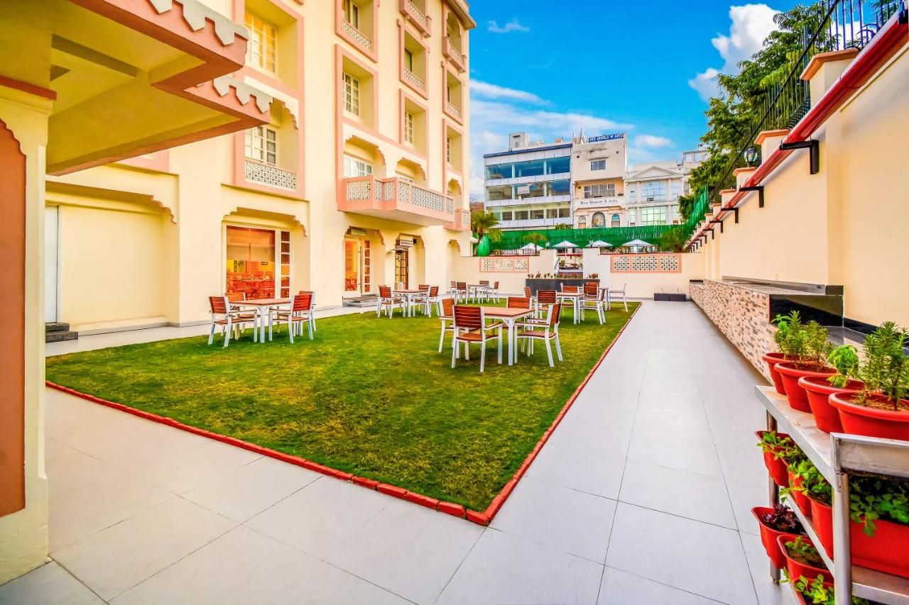 A courtyard with outdoor seating, a lawn, and a building with balconies.