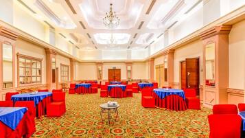 A conference room with tables and chairs, a patterned carpet, and a chandelier.