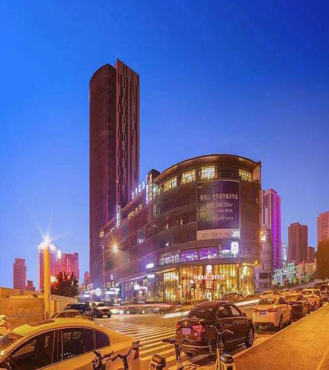 Un immeuble à plusieurs étages, doté d’une enseigne lumineuse, d’une structure verticale imposante et d’une façade incurvée.