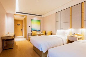 Ein Hotelzimmer mit zwei Betten, einem Schreibtisch, einer Couch und einem großen Gemälde an der Wand.