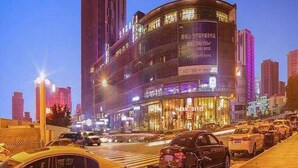 A multi-story building with illuminated signage, a prominent vertical structure, and a curved facade. - JI Hotel Chongqin Liangjiang Xingfu Plaza (Chongqing)