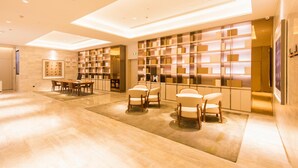A modern hotel lobby with a reception desk, seating area, and a large bookshelf. - JI Hotel Chongqin Liangjiang Xingfu Plaza (Chongqing)