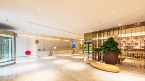 A modern hotel lobby with a reception desk, a large potted plant, and a seating area with a glass wall. - JI Hotel Chongqin Liangjiang Xingfu Plaza (Chongqing)