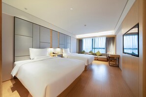 Habitación de hotel con dos camas, un escritorio y un ventanal grande con cortinas.