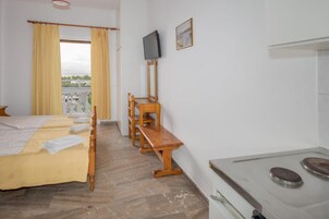 Una habitación de hotel con cama, banca de madera, televisor y estufa.