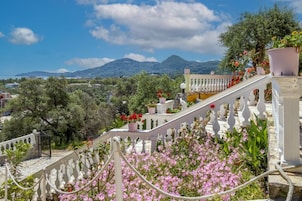 A staircase with white balustrades leading to a balcony with potted plants and flowers.