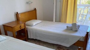 A hotel room with two single beds, a wooden nightstand, and a window with curtains. - Corfu Panorama (Corfu)