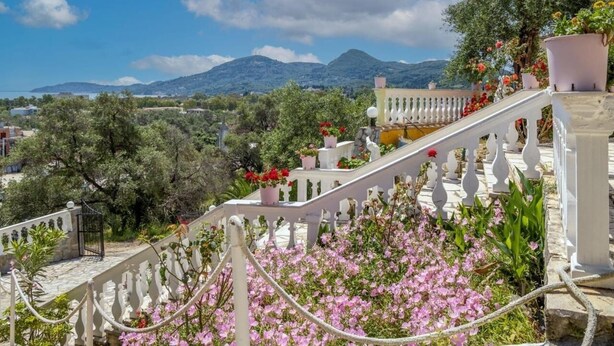 A staircase with white balustrades leading to a balcony with potted plants and flowers. - Corfu Panorama (Corfu)