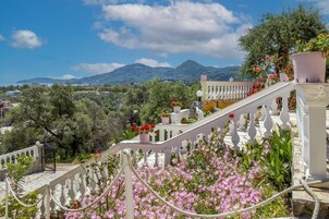 A staircase with white balustrades leading to a balcony with potted plants and flowers.