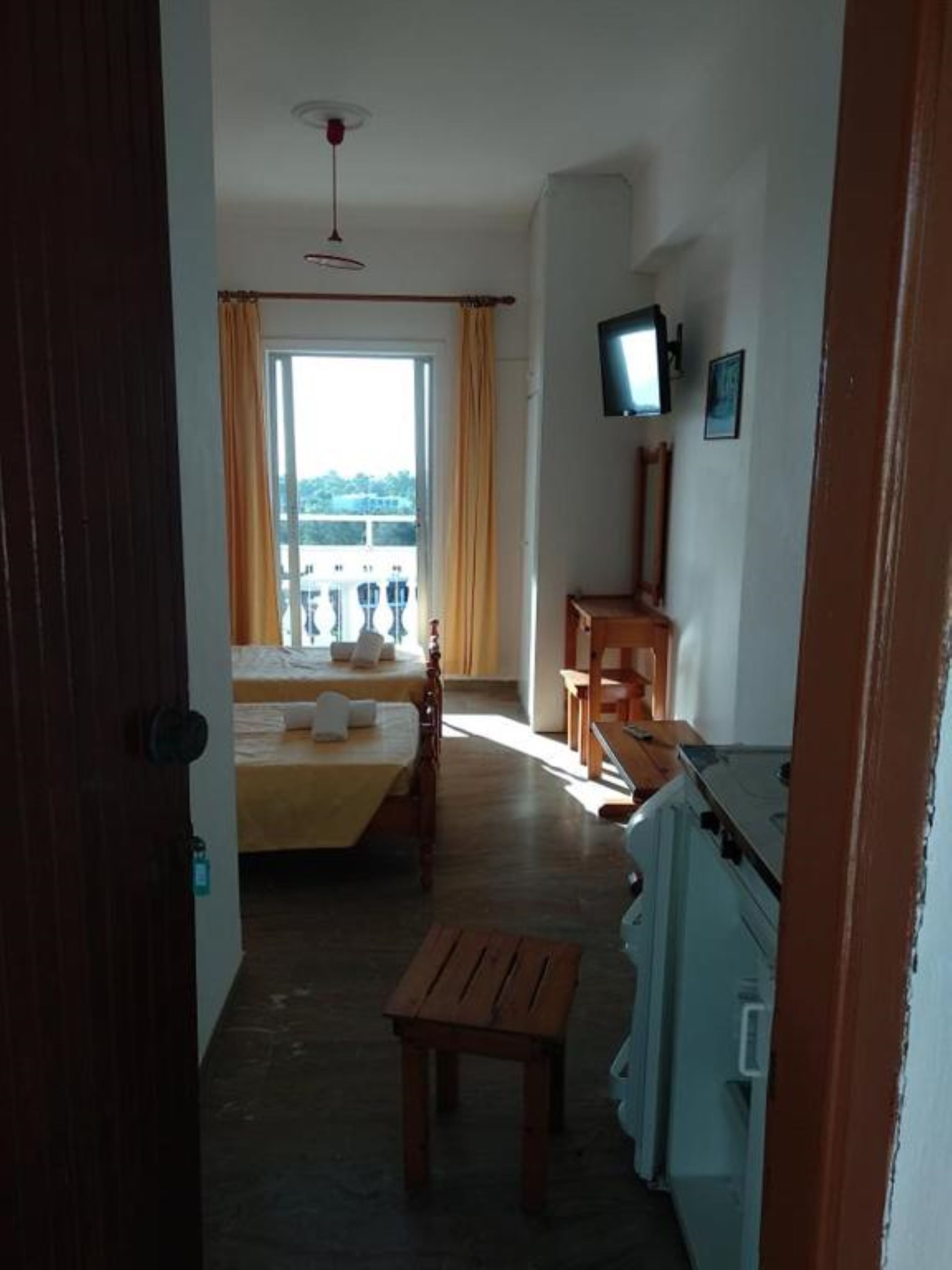 Et hotelværelse med seng, skrivebord, fjernsyn og en balkon med udsigt.