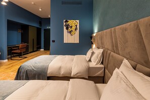 Habitación de hotel con una cama grande, un escritorio y una silla. Hay un cuadro en la pared y una ventana con persianas.