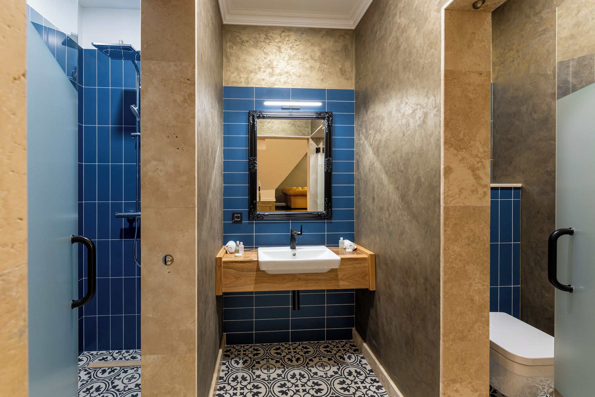 A bathroom with a shower, a sink with a mirror, and a toilet.