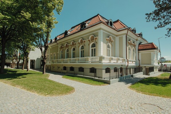 A historic building with a symmetrical facade, arched windows, and a central balcony.