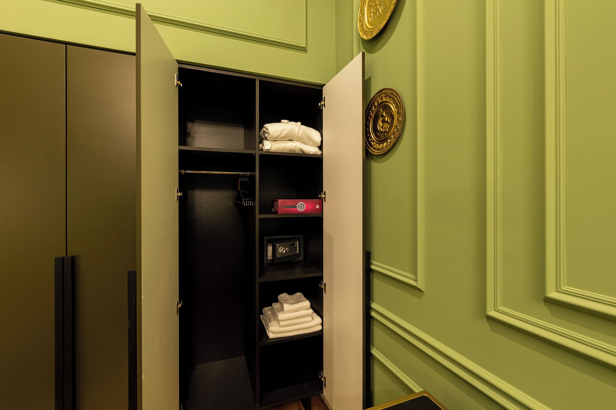 A walk-in closet with shelves, a safe, and neatly folded towels.