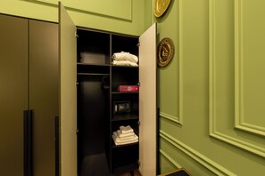 Un armario vestidor con repisas, una caja fuerte y toallas dobladas con cuidado.