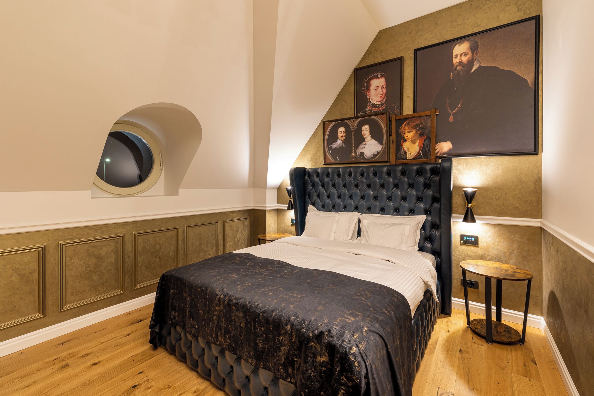 Un dormitorio con una cama grande, un espejo redondo y retratos enmarcados en la pared.
