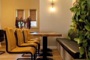 A dining area with a long table and multiple chairs, a bench, and a plant. - Boutique Hotel Cocosul De Aur (Târgu Mureș)