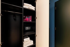Un armario de hotel con toallas dobladas con cuidado, un secador de pelo y una caja de productos para el cabello.