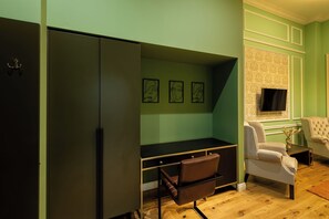 Una habitación con escritorio, silla, televisor y armario.