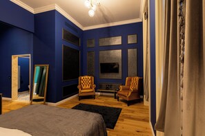 Una habitación con una cama grande, dos sillones, un televisor y una chimenea.