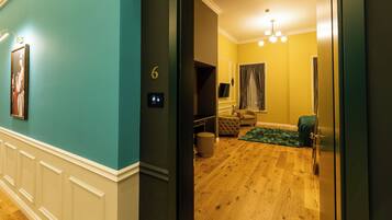 A room with a wooden floor, a green sofa, a television, and a door leading to another room.