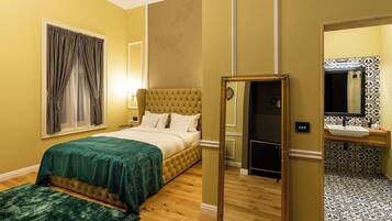 A hotel room with a bed, a bedside table, a mirror, and a bathroom with a sink and toilet.