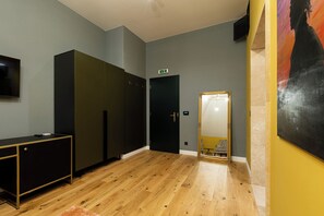 A room with a wooden floor, a black and gold cabinet, a door with an emergency exit sign, and a large mirror with a gold frame. - Boutique Hotel Cocosul De Aur (Târgu Mureș)