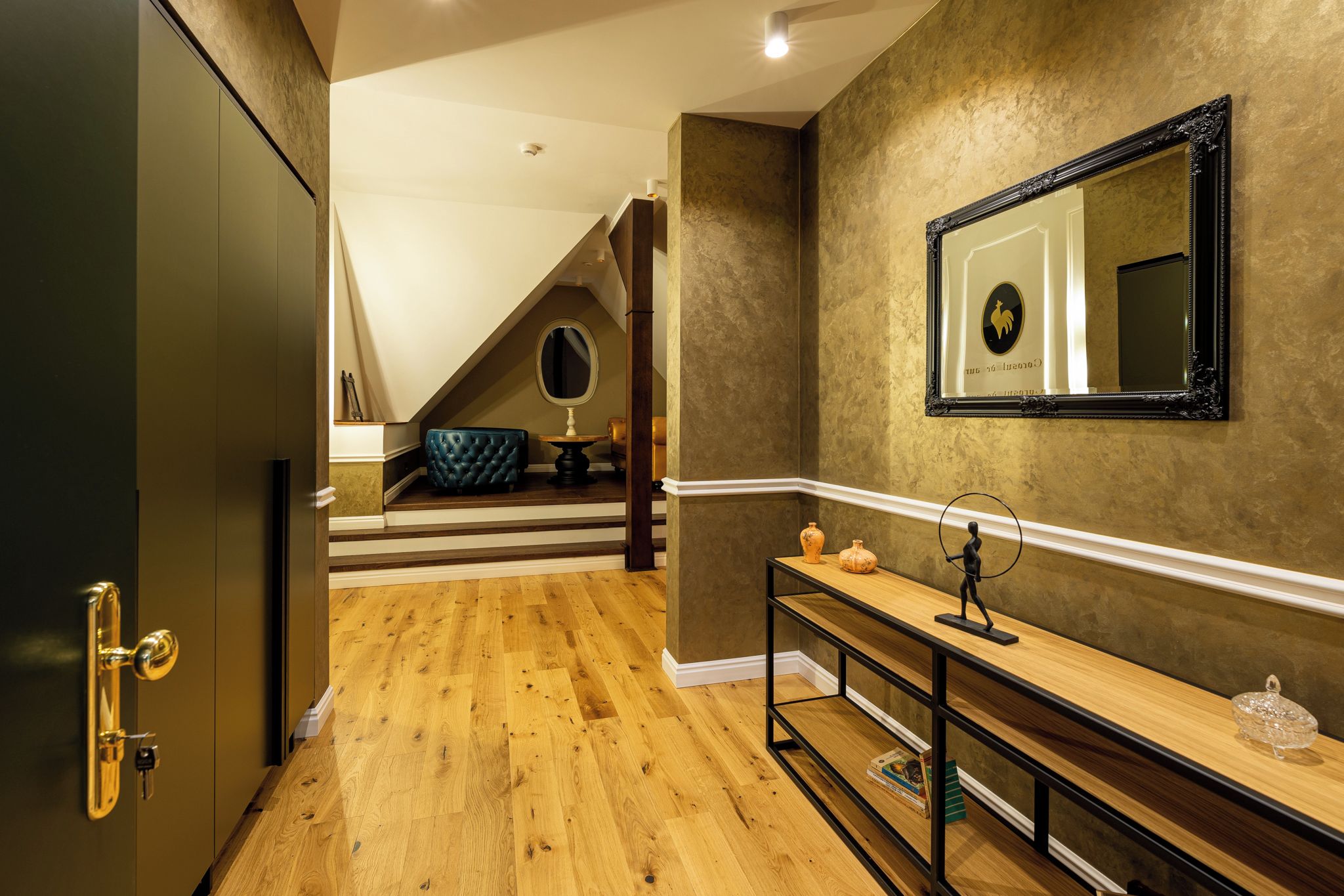 Ein modernes Interieur mit Holzboden, einem Waschtisch mit Spiegel und einer Treppe, die in eine obere Ebene führt.
