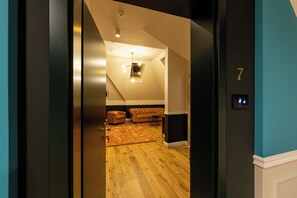 A hallway leading to a room with a wooden floor, a leather sofa, and a small table. - Boutique Hotel Cocosul De Aur (Târgu Mureș)
