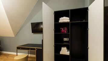 A room with a desk, a wardrobe, and a television.