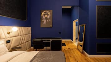 A bedroom with a bed, bedside table, dresser, and a large mirror.