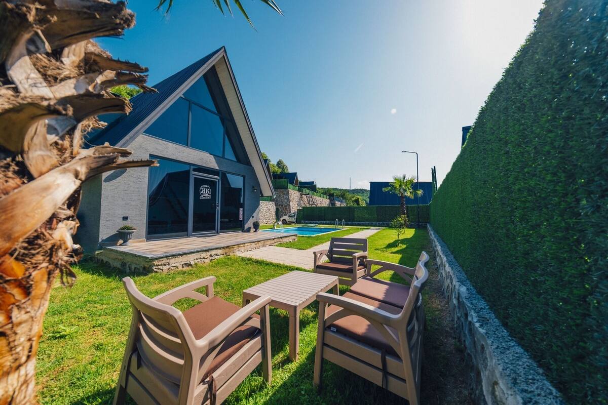 Un edificio moderno con piscina, mobiliario exterior y un césped cuidado.