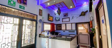 A reception area with a counter, a clock, framed pictures, and a fire extinguisher.