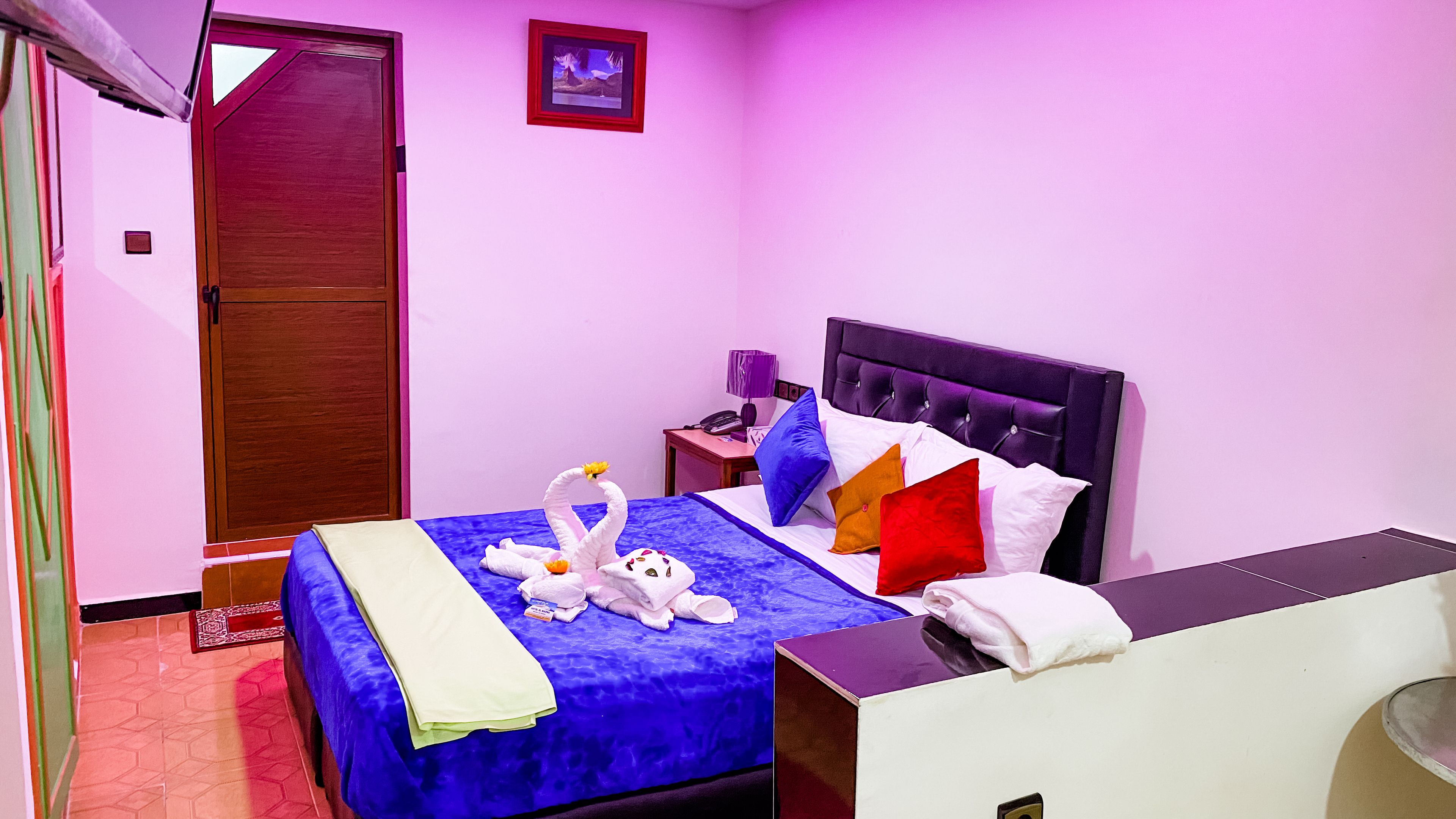 Una habitación de hotel con cama, mesita de noche, lámpara y puerta.