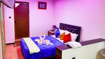 Una habitación de hotel con cama, mesita de noche, lámpara y puerta.