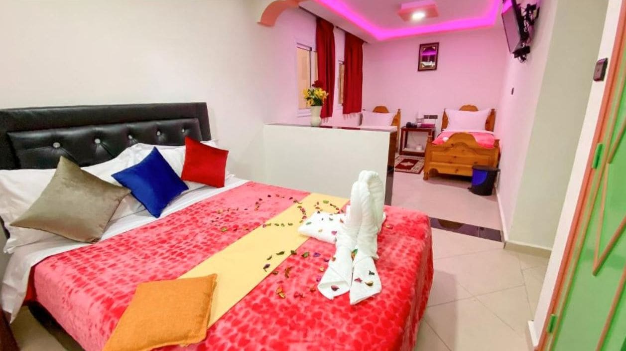 Une chambre d’hôtel avec un lit, une table de chevet, une télévision et une salle de bain à l’arrière-plan.