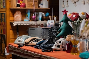 A room with a desk, various items including a telephone, a radio, a small Christmas tree, and a vase with flowers.