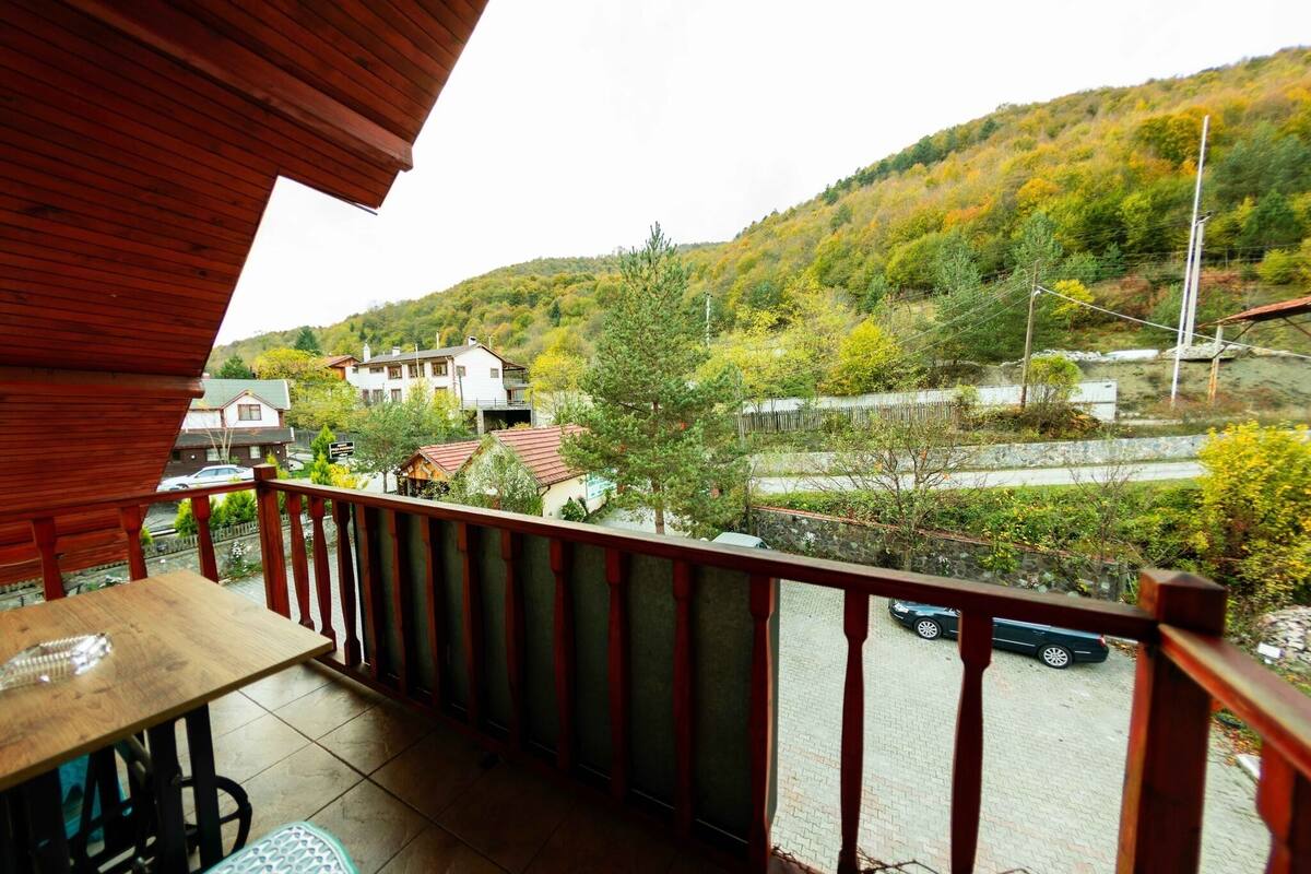 Ein Balkon mit Blick auf ein Wohngebiet, ein Tisch und ein Auto, das auf der Straße geparkt ist.