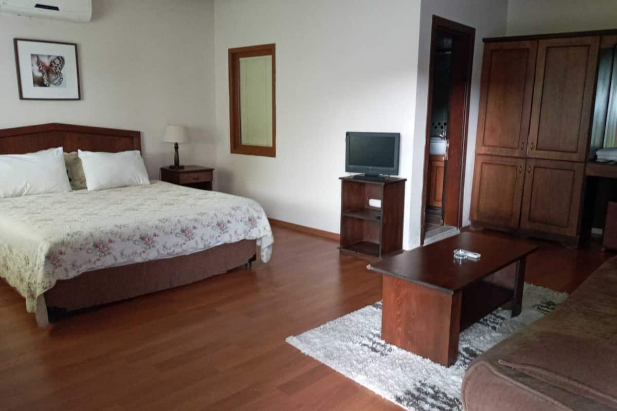 A bedroom with a bed, bedside table, lamp, TV stand, and a wardrobe.